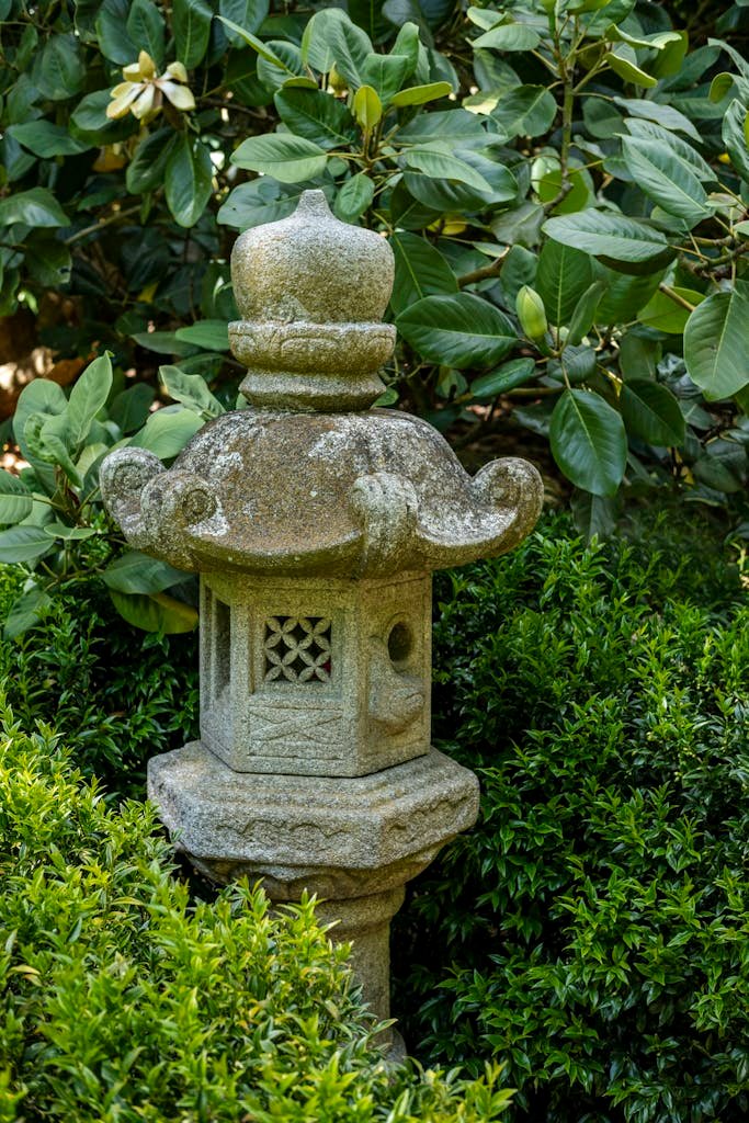 A serene Japanese garden scene featuring a traditional stone lantern surrounded by vibrant greenery.